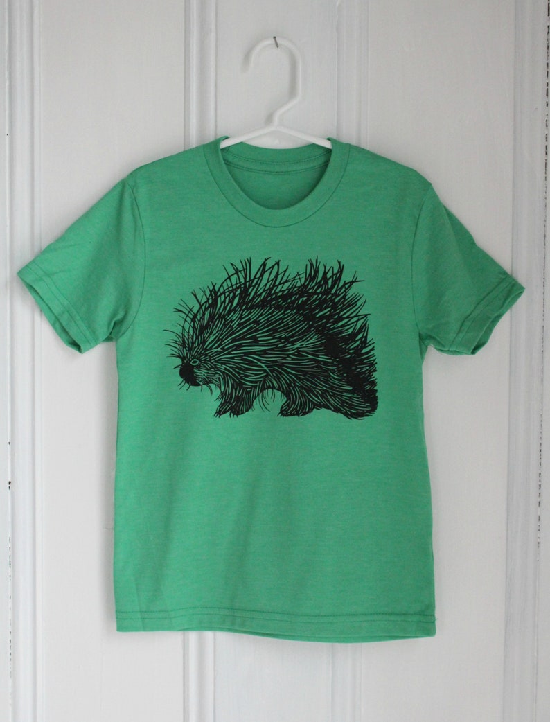 May include: A green t-shirt with a black and white illustration of a porcupine.