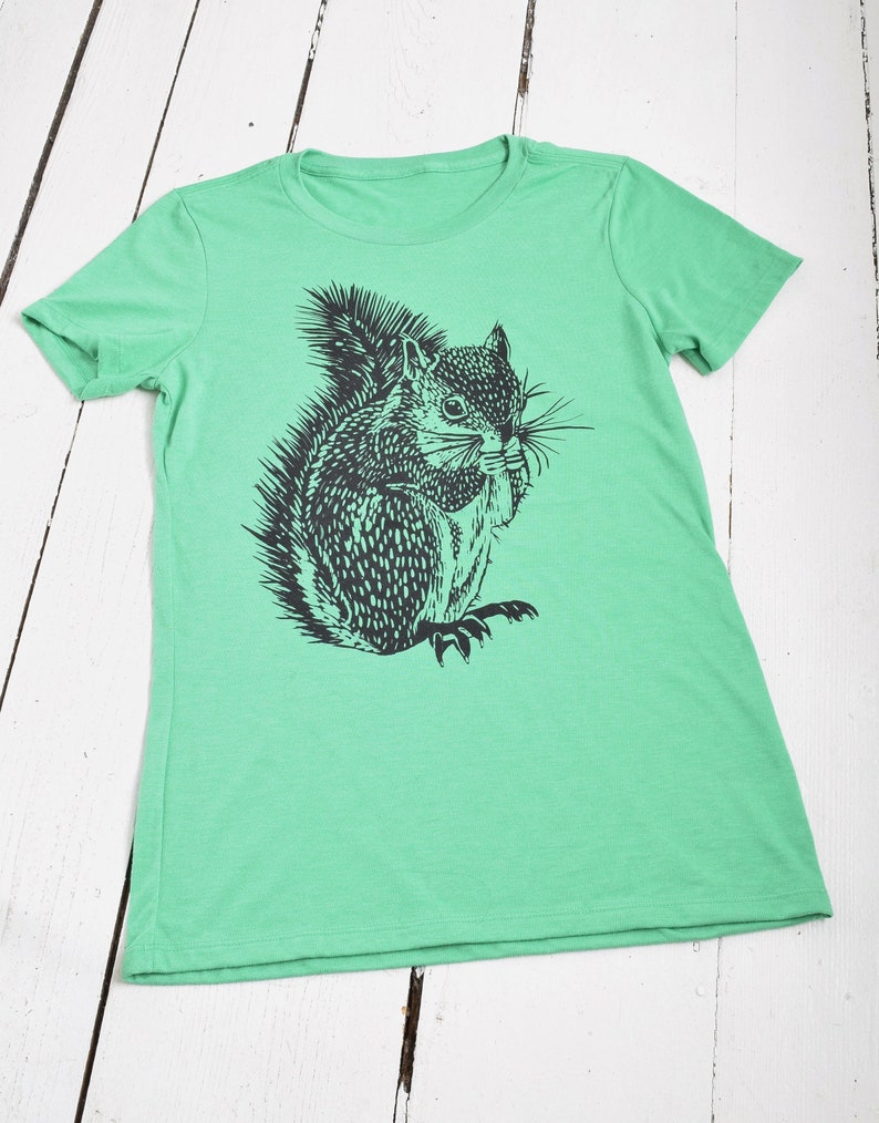 May include: A green t-shirt with a black and white illustration of a squirrel on the front.
