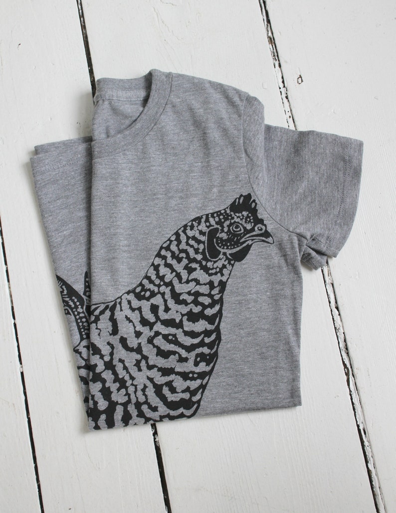 May include: A gray t-shirt with a black and white illustration of a chicken on the front.
