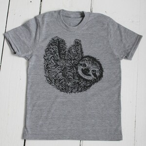 May include: A gray t-shirt with a black and white illustration of a sloth hanging upside down.