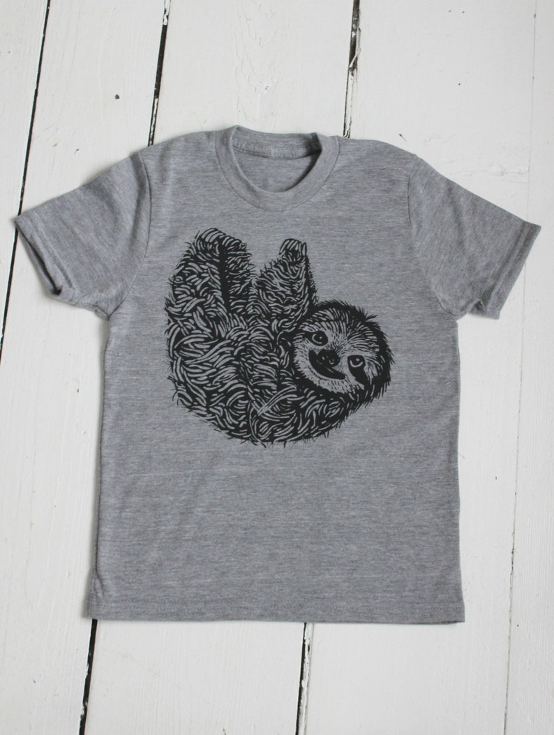 May include: A gray t-shirt with a black and white illustration of a sloth hanging upside down.