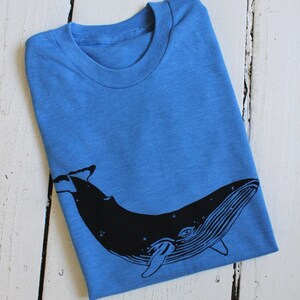 May include: A blue t-shirt with a black whale graphic printed on the front.