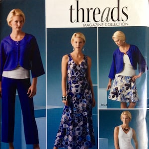 May include: A sewing pattern for a dress, a top, and a skirt. The pattern is from the Threads Magazine Collection and is for sizes K5 8, 10, 12, 14, 16. The pattern is for a dress with a blue and white abstract print, a blue top with a white collar, and a white skirt with a blue and white floral print.