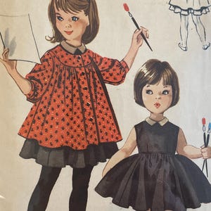 May include: Vintage McCall's printed pattern for a child's dress and smock, designed by Helen Lee. The pattern features illustrations of two young girls, one in a red dress with black accents and the other in a black dress. The pattern number is 5127, size 5.