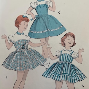 May include: Vintage Butterick sewing pattern featuring illustrations of three girls in dresses. The pattern includes a blue dress with white trim, a plaid dress, and a striped dress. The pattern is for a size 2 with a 21-inch breast.