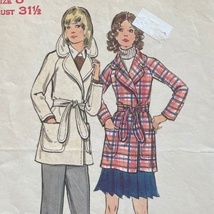 May include: Vintage sewing pattern for a women's coat. The pattern is for size 8 with a 31 1/2 inch bust. The pattern shows two women wearing the coat, one in a white coat and the other in a plaid coat. The pattern is from the brand Butterick, The Fashion One. The pattern number is 6528 and the price is $1.00.