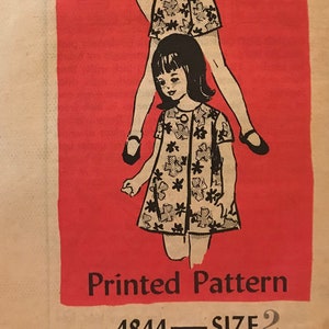 May include: Vintage sewing pattern for a girl's dress and shorts set. The pattern is printed on a tan paper with a red background. The pattern number is 4844 and the size is 2.