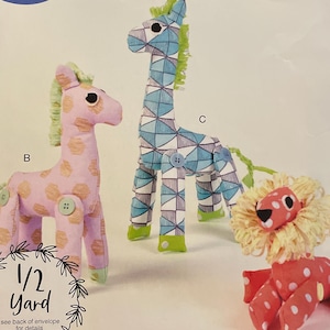 May include: A McCall's sewing pattern featuring instructions for making three stuffed animal toys: a giraffe, a lion, and another giraffe. The pattern includes the text "IT'S Sew SIMPLE" and "MADE IN USA".