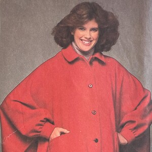 May include: Vintage Simplicity sewing pattern, size K (8, 10, & 12), featuring a red cape with a collar and button closure. The pattern is labeled "ESP Extra-Sure Pattern" and includes the price of 95p.