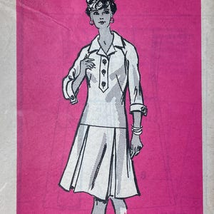 May include: A white ceramic mug with a black handle and the text "But First, Coffee" in a black, handwritten-style font. The mug is on a white surface.