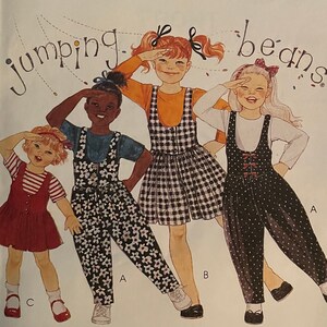 May include: A sewing pattern for children's clothing, featuring four girls wearing different outfits. The pattern is titled "Jumping Beans" and includes instructions for making a t-shirt, overalls, and a skirt. The pattern number is 6129.