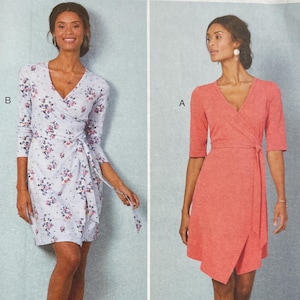 May include: McCall's sewing pattern M7893 featuring two wrap dresses. One dress is light blue with a floral print, and the other is a solid coral color. The pattern includes sizes 18W-24W. Nancy Zieman Productions.