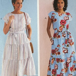 May include: A vintage Butterick sewing pattern featuring two dress designs. One dress is a button-down style with a striped pattern, and the other is a floral print dress. The pattern number is B6722, with sizes A5 (6-8-10-12-14).