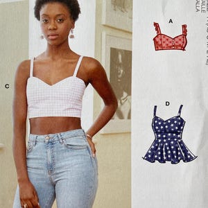 May include: McCall's sewing pattern package featuring a woman wearing a gingham crop top and jeans. The package includes pattern views for tops with different designs. The text on the package reads "McCall's" and "#WrenMcCalls".