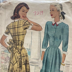 May include: Vintage McCall's sewing pattern for a dress, pattern number 7219. The pattern shows two women wearing dresses, one in a plaid print and the other in a solid blue color. The pattern is printed on a yellowed paper with the text "McCall's Printed Pattern" in the top right corner.