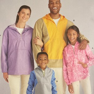 May include: Simplicity sewing pattern S9481 showing a family in pullovers. The pattern includes sizes XS-XL. The image displays a family of four wearing various coloured pullovers: purple, yellow, pink, and blue. The pattern also shows different pullover designs.
