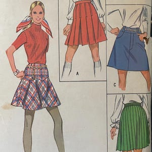 May include: Vintage McCall's 2233 sewing pattern for misses' skirts. The pattern features illustrations of different skirt styles, including a pleated red skirt, a denim skirt, and a green pleated skirt. The pattern includes sizing information: waist 23 inches, hip 33.5 inches.