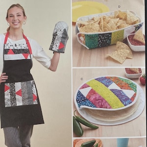 May include: Simplicity sewing pattern S9942 featuring a black apron with a red strap, oven mitt, and various kitchen accessories. The pattern includes instructions for a tortilla warmer, chip basket, and placemat.