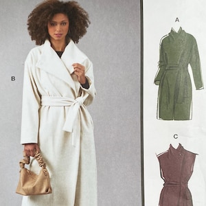 May include: A sewing pattern package featuring a woman wearing a cream-colored wrap coat with a tie belt. The package includes illustrations of coat variations in green and brown. The text reads "McCall's" and "Designed and printed in USA."