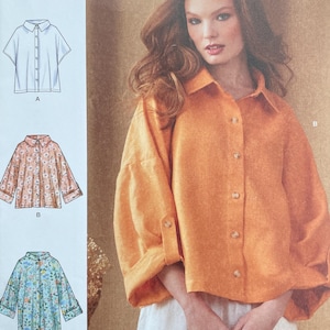 May include: Simplicity sewing pattern S9952. The pattern features a woman wearing an orange button-down shirt and white pants. The pattern includes illustrations of different shirt styles. The text "easy-to-sew" is visible.
