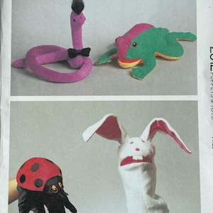 May include: A Kwik Sew pattern envelope, Pattern 2312, featuring puppets and toys. The image shows a purple snake puppet with a black bow tie, a green and pink frog puppet, a ladybug puppet, and a white bunny puppet.