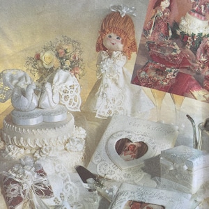 May include: Simplicity Crafts pattern featuring wedding-themed crafts. The image showcases a doll in a wedding dress, a wedding cake, photo frames, and a small gift box. The pattern includes designs for various handmade wedding decorations.
