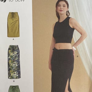 May include: Simplicity sewing pattern S9788 featuring a skirt design. The pattern includes sizes U.S. 10-22. The image shows a woman wearing a black crop top and a black skirt with a side slit. The pattern is easy-to-sew.
