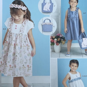 May include: Simplicity sewing pattern S9559 featuring children's clothing designs. The pattern includes a dress, top, and pants, with a matching tote bag. The designs are shown on young girls, with floral and denim fabrics. The text "easy-to-sew" is also visible.