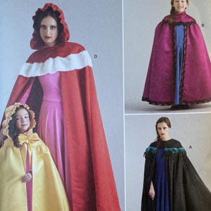 May include: Simplicity Costumes sewing pattern S9626. The pattern features images of capes in red, yellow, and black. The capes have decorative trim and hoods. The pattern includes sizes S-L/XS-XL.