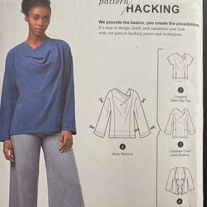 May include: Simplicity sewing pattern S8991 A, showing a woman in a blue top and grey trousers. The pattern includes instructions for a cropped shirt, cowl with pockets, and a waterfall jacket. The text reads "pattern hacking".