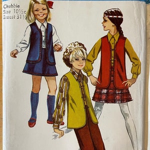 May include: Simplicity sewing pattern number 8428 for children's clothing. The pattern includes three different outfits: a blue vest with a skirt, a red vest with a plaid skirt, and a yellow vest with brown pants. The pattern is for sizes 10 1/2 to 31 1/2.