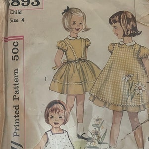 May include: Simplicity Printed Pattern 50c sewing pattern for a child's dress. The pattern shows three different styles of dresses, all with a gingham or floral print. The pattern number is 893 and the size is 4.