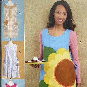 May include: McCall's sewing pattern for aprons. The pattern includes multiple apron designs, including a blue apron with a sunflower design, a gingham apron, and aprons with floral and heart details. Sizes available: XS-XL.