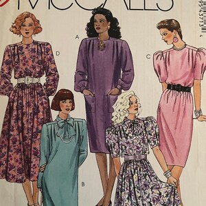 May include: Vintage McCall's sewing pattern envelope with dress illustrations. The cover shows five dress designs in different colours and floral patterns. The text "Fashion Basics" and "Cut-to-Fit" are also visible on the envelope.