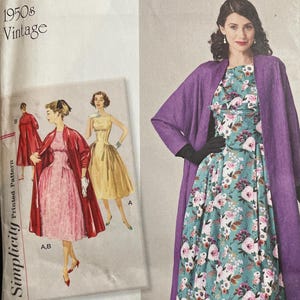 May include: A Simplicity 8731 sewing pattern envelope for 1950s vintage clothing. The cover features illustrations of a floral print dress and a solid purple coat, with size U.S. 6-14 printed at the top. The text includes Simplicity 8731.