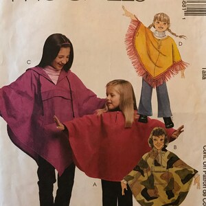 May include: A sewing pattern for making ponchos for children. The pattern includes three different styles: a purple poncho, a red poncho, and a camouflage poncho. The pattern is for sizes X-Small to Small.