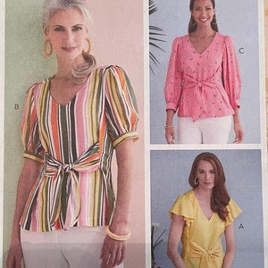 May include: A Butterick sewing pattern featuring three blouse designs. One blouse is striped with a tie waist, another is pink with a floral print, and the third is yellow with ruffled sleeves. The pattern number is B6731.