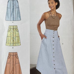 May include: Simplicity sewing pattern S9710 featuring three skirt designs. The pattern includes sizes U.S. 8-16 and European sizes 34-44. The image shows a woman wearing a button-down skirt. The pattern is designed and printed in the USA.