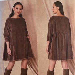 May include: Vogue Patterns sewing pattern V1821 featuring a brown dress with a loose fit and three-quarter sleeves. The pattern includes sizes XS to XXL. The model is wearing the dress with brown knee-high boots. The brand is Rachel Comey.