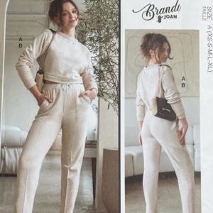 May include: A McCall's sewing pattern featuring a two-piece outfit designed by Brandi Joan. The pattern includes a long-sleeved top and pants in sizes XS-XL. The image shows a woman wearing the outfit in a light beige color. The pattern is designed and printed in the USA.