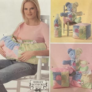 May include: Simplicity sewing pattern number 4075, one size, for a baby carrier, a teddy bear, a bottle, and a block. The pattern includes instructions for making a baby carrier, a teddy bear, a bottle, and a block. The pattern is from Shirley Botsford Designs.