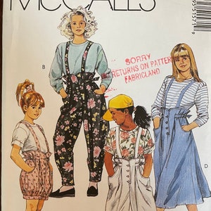 May include: A sewing pattern for a girl's overalls. The pattern includes three different styles of overalls: one with a floral print, one with a striped print, and one with a solid white print. The pattern is for size 7.