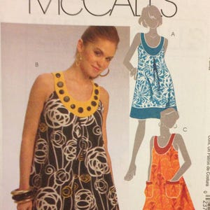 May include: McCall's M5659 sewing pattern featuring a woman wearing a black and white floral print dress with a yellow collar. The pattern includes illustrations of similar dresses in blue and orange. Size B5 (8-10-12-14-16).