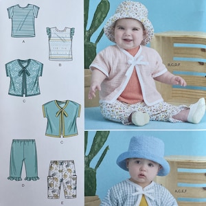 May include: Simplicity sewing pattern S9616 with baby clothing designs. The pattern includes tops, trousers, and hats. The image shows a baby wearing a light pink jacket and floral hat, and another baby wearing a blue hat and jacket.