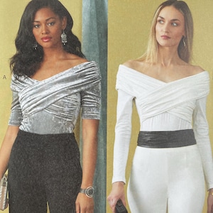 May include: Vogue Patterns sewing pattern featuring two off-the-shoulder tops and pants. The pattern includes a short-sleeved, silver-gray top paired with black pants, and a long-sleeved white top with white pants and a black belt. The pattern size is B5 (8-10-12-14-16).