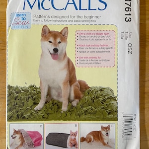 May include: Sewing pattern for a dog bed, featuring a Shiba Inu dog sitting on a green bed, a pink and brown dog bed, a gray and white dog bed, and a brown and white dog bed. The pattern includes instructions for sewing a circle to a straight edge, attaching hook and loop fasteners, and sewing with synthetic fur.