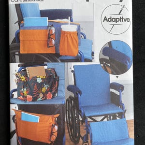 May include: Simplicity sewing pattern S9492 for adaptive wheelchair accessories. The pattern includes instructions for creating various items, such as a bag, cup holder, and armrest covers. The image shows the finished products in orange and blue.
