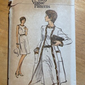May include: Vintage Vogue Patterns sewing pattern. The cover features illustrations of women's dresses and coats. The text on the cover reads "Very Easy Vogue Patterns" and "Size 16". The cover is beige with brown and black accents.