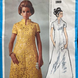 May include: A vintage Vogue Americana sewing pattern featuring a yellow floral print dress and a white dress illustration. The pattern is labeled "1909" and designed by Oscar de la Renta. The image is set against a blue background.