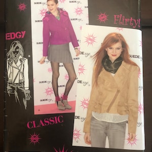 May include: A sewing pattern for a jacket and skirt. The pattern is called "Suede Says" and features two models wearing the garments. The jacket is a brown leather-look jacket with a zipper closure. The skirt is a gray pleated skirt. The pattern is for sizes 14-22.